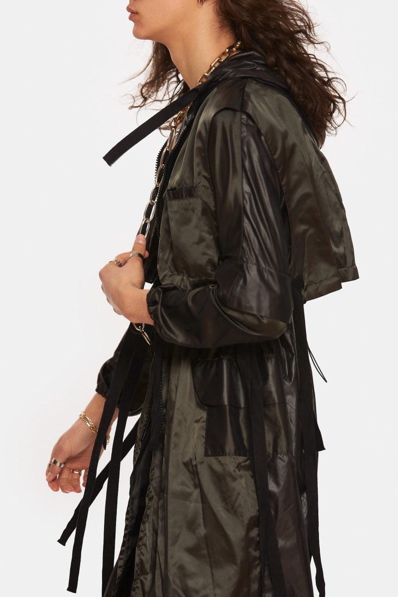 Unlined trench coat made from a black slicker with hood. Notch lapels with adjustable cords. Front zipper with double openings. Adjustable elastic cord at the waist. Water repellant.