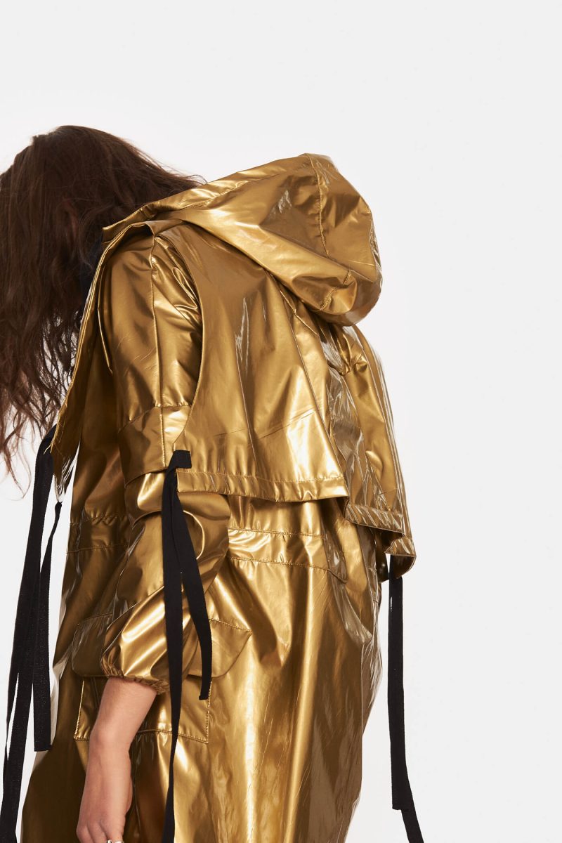 Unlined trench coat made from a gold slicker with hood. Notch lapels with adjustable cords. Front zipper with double openings. Adjustable elastic cord at the waist. Water repellant.